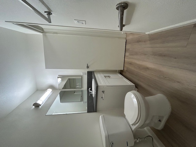 A white toilet with a wooden wall behind it.